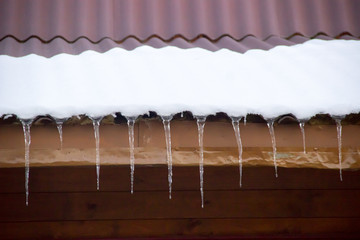 icicles on snow covered roof of a village house in the winter