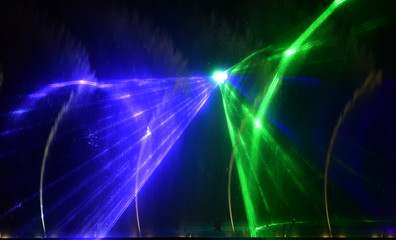 Colorful water fountains. Beautiful laser and fountains show. Large multi colored decorative dancing water jet led light fountain show at night. Dark background.