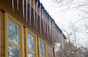 icicles on snow covered roof of a village house in the winter