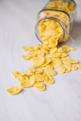 Corn flakes in a glass jar on white wooden surface. Top view. Place for your text