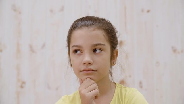 Portrait thoughtful girl looking away on a light background in studio. Close up face pensive girl teenager. Young people emotions concept