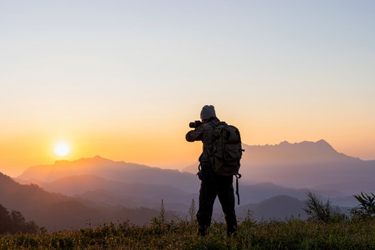 Nature photographer take photos with mirror camera on peak of mountain at morning sunrise