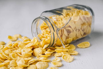 Corn flakes in a glass jar on white wooden surface. Top view. Place for your text