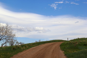 Fototapeta na wymiar road in the field wirh blue sky and clouds