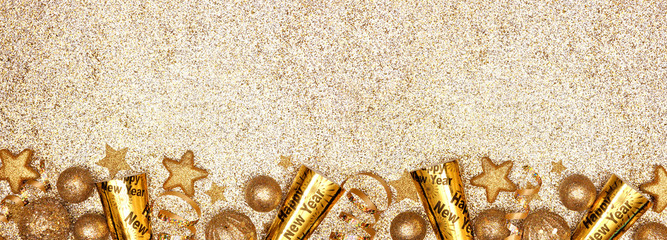 New Years Eve border banner of gold decorations, steamers and noisemakers. Above view over a...