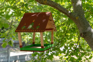 Selfmade bird feeding house hangs on the left Prelesne Shadow shade tree