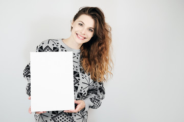Happy european girl holding a blank vertical canvas in her hands. Empty frame for text or photo....