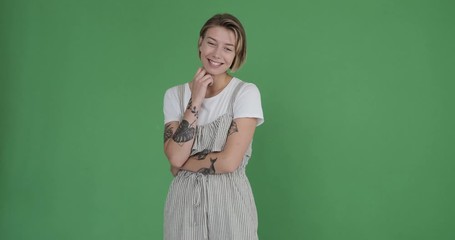 Beautiful tattooed woman posing in frill dungarees over green background