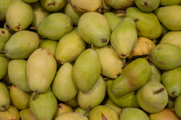 Bartlett pears in a supermarket. A bunch of green ripe fresh pear fruits. Background backdrop, many pears