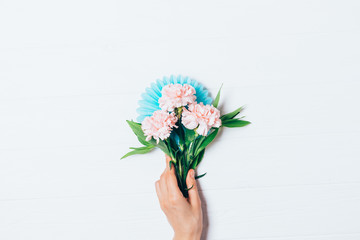 Female hand holding festive bouquet of pale pink carnation flowers