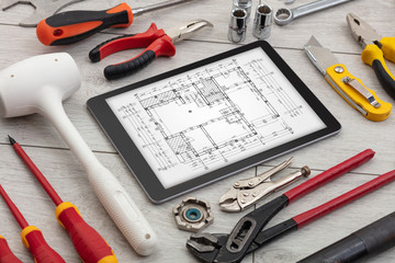 Tablet with construction tools and blueprint concept