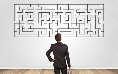 Businessman in doubt looking to a maze and searching the way out