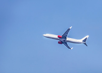White commercial airplane flying away in to clear sky  travel destinations concept.