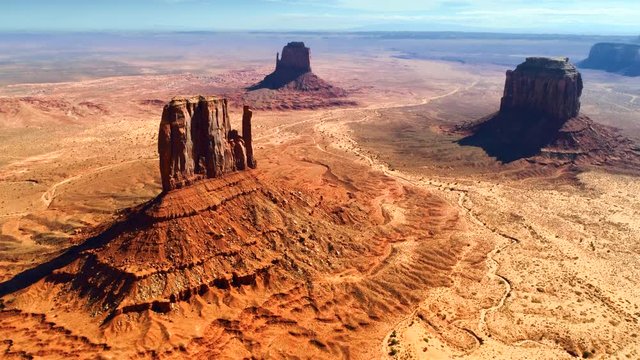 Magnificent aerial view of three giant stone monuments of Monument Valley. Famous valley in the Navajo Reservation with red sandstone outcrops, located on the border of Arizona and Utah states. 4K