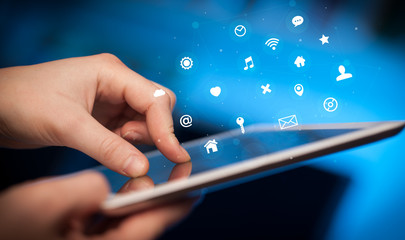 Hand holding tablet with multimedia and application symbols concept