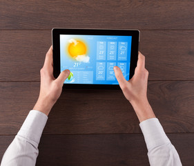 Man hand checking weekly weather forecast on tablet