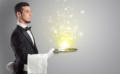 Elegant young waiter serving mysterious light on tray
