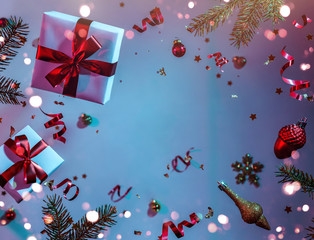 Fototapeta na wymiar Merry Christmas and New Year background. Xmas holiday card made of flying decorations, fir branches, balls, snowflakes, sparkles, gift boxes, bokeh on colorful neon blue and purple background