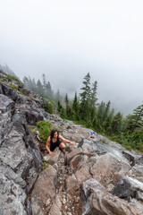 Adventurous Girl is hiking in beautiful green woods in the mountains during a cloudy summer morning. Taken on Crown Mountain, North Vancouver, BC, Canada.