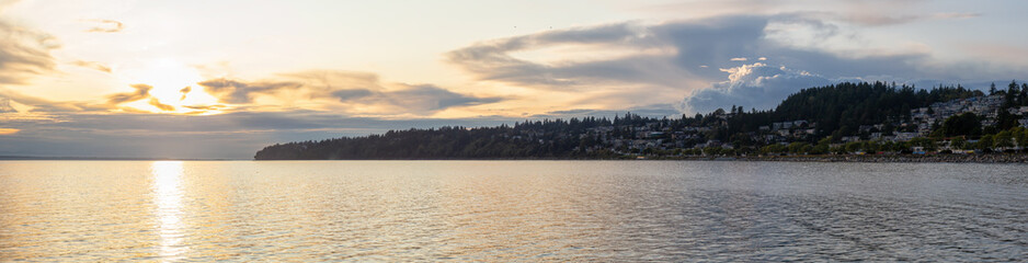 Fototapeta premium White Rock, British Columbia, Canada. Beautiful Panoramic View of Residential Homes on the Ocean Shore during a sunny and cloudy summer sunset.