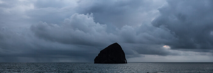 Naklejka na ściany i meble Pacific City, Oregon, United States of America. Beautiful Panoramic View of Chief Kiawanda Rock on the Ocean Coast during a cloudy summer sunset.