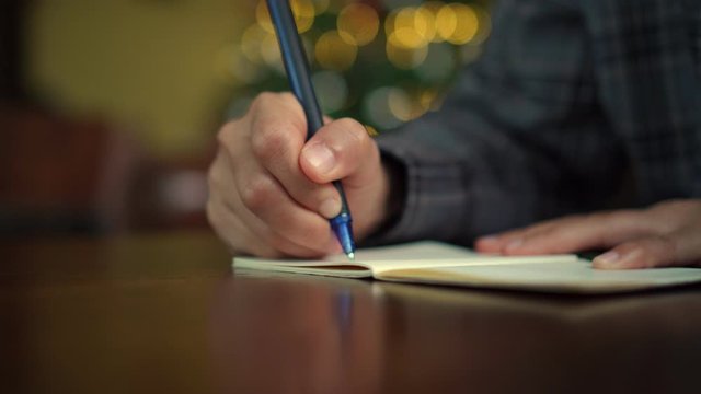 4k video woman hand writing down in white notebook to plan work on table with bokeh light in cafe background.