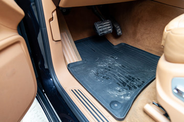 Dirty car floor mats of black rubber with gas pedals and brakes in the workshop for the detailing...