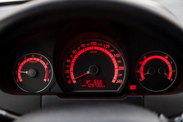 The dashboard of the car is glowing white with orange arrows at night with a speedometer, tachometer and other tools to monitor the condition of the vehicle in classic style