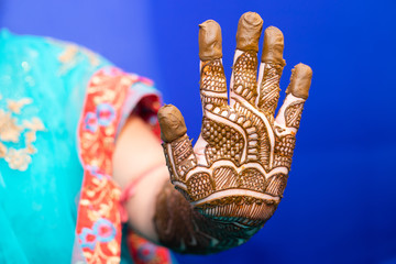 young woman mehendi artist painting henna on bride's hand before wedding day
