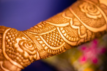 young woman mehendi artist painting henna on bride's hand before wedding day