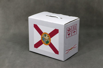Florida flag on white box and state flag barcode with fragile symbol on grey background. The concept of export trading from Florida.