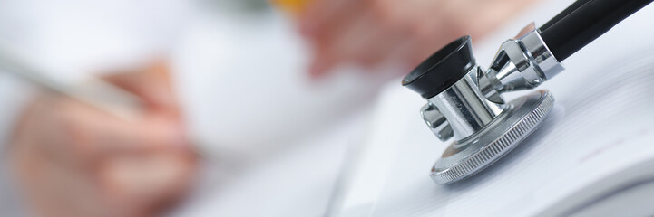 Stethoscope head lying on medical forms