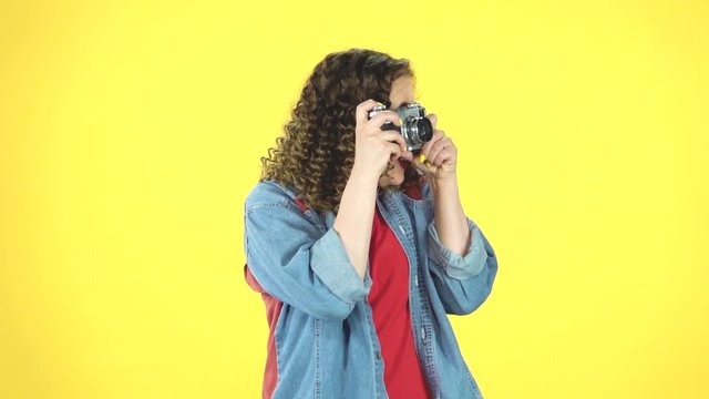 Smiling girl is shooting pictures on a retro photo film camera. Retro style, slow motion