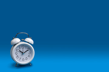 a white alarm clock with a dark blue background.