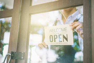 Store owner turning open sign broad through the door glass and ready to service. man with open banner at cafe or restaurant window.