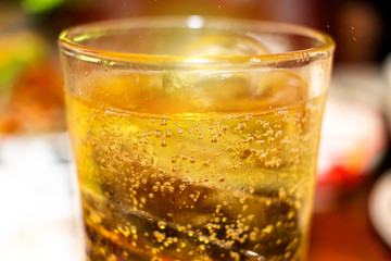 Glass of Whisky (whiskey), bourbon, ice tea or coke (cola) soda with ice and water drops on wood table at blur background