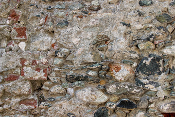 Texture of an old heavily damaged stone wall coated with cement residues