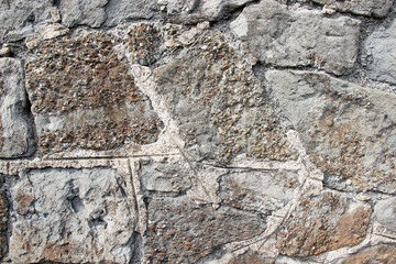 Texture of an old stone wall made of pebblestone coated with cement residues