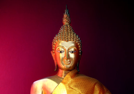 gold bhuddha statue close up smile face on vintage dark red background low key style