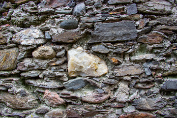 Wall made of natural rocks with big white stone in the center