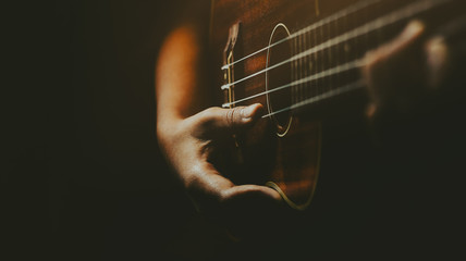Hands playing acoustic ukulele guitar