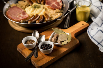 Sauerkraut Gewürze Lorbeer, Kümmel, Muskat, Wacholderbeeren mit Kraut Pfanne Nürnberger Rostbratwürste, Kassler Nacken,  Kartoffelpüree auf Holz Tisch
