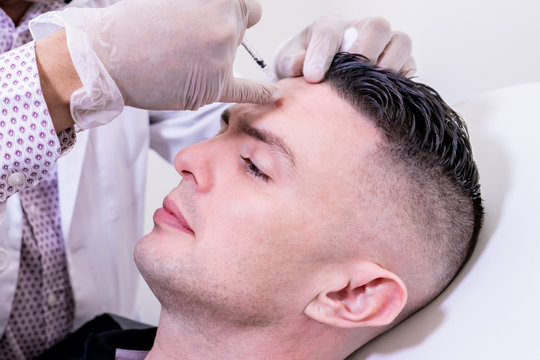 Caucasian man undergoing beauty spa botulinum neurotoxin Botox treatment for anti-aging, to smooth wrinkles as a cometic solution. Injecting forehead to relax muscles with a non-invasive procedure.