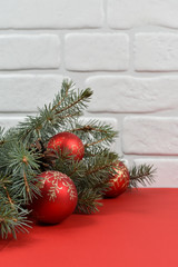 New Year's decoration. Red balls, Christmas tree, white wall, red background.