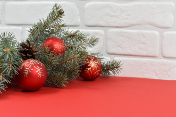 New Year's decoration. Red balls, Christmas tree, white wall, red background.