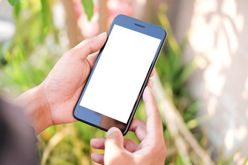 Cropped shot view of man hands holding smart phone with blank copy space screen for your text message or information content, female reading text message on cell telephone during in urban setting. 