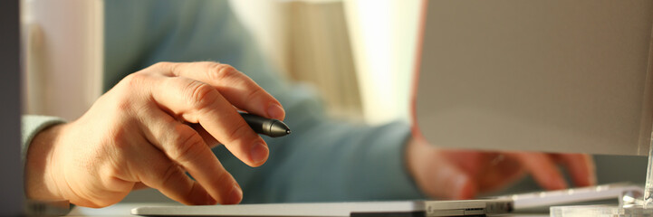 A young designer holds a pen from a tablet in his