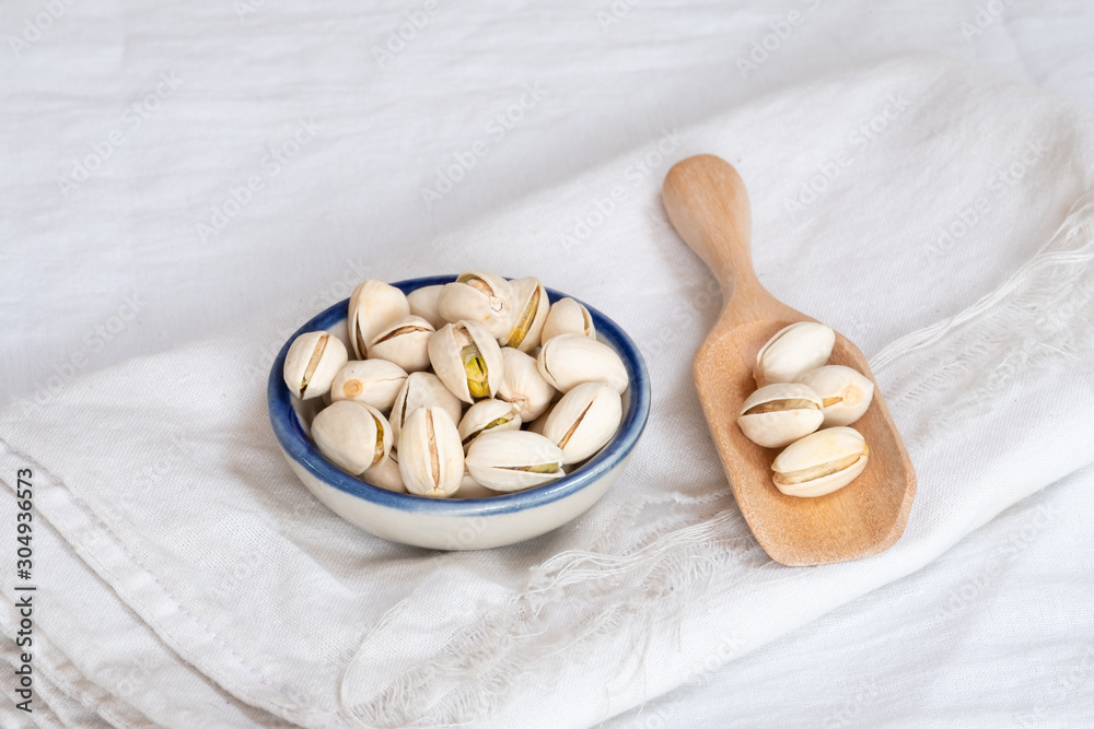 Wall mural Pistachio nut in wooden bowl on white table background - Wall murals