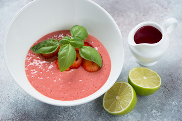 White bowl of strawberry cream-soup over beige stone background, studio shot