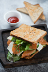 Close-up of sandwich with grain bread, salmon, cheese and vegetables, selective focus, vertical shot